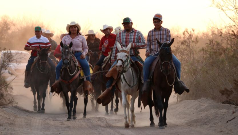 Personas participan en una cabalgata sobre un camino de terracería en La Paz, Baja California Sur.
